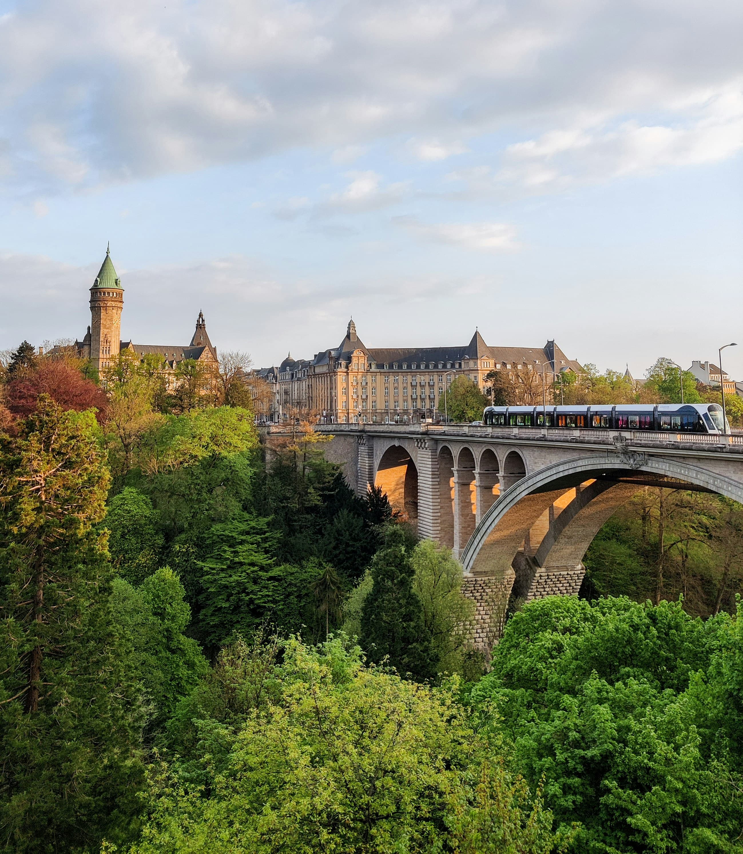 The Pont Adolphe and the old town of Luxembourg, a tram crossing the bridge.